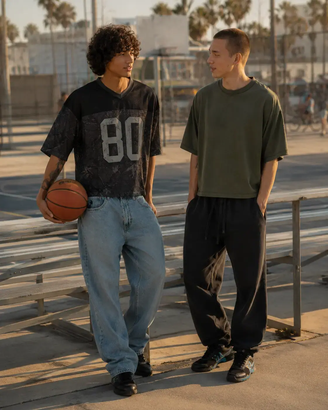 Two men in RSQ tops on an outdoor basketball court at sunset