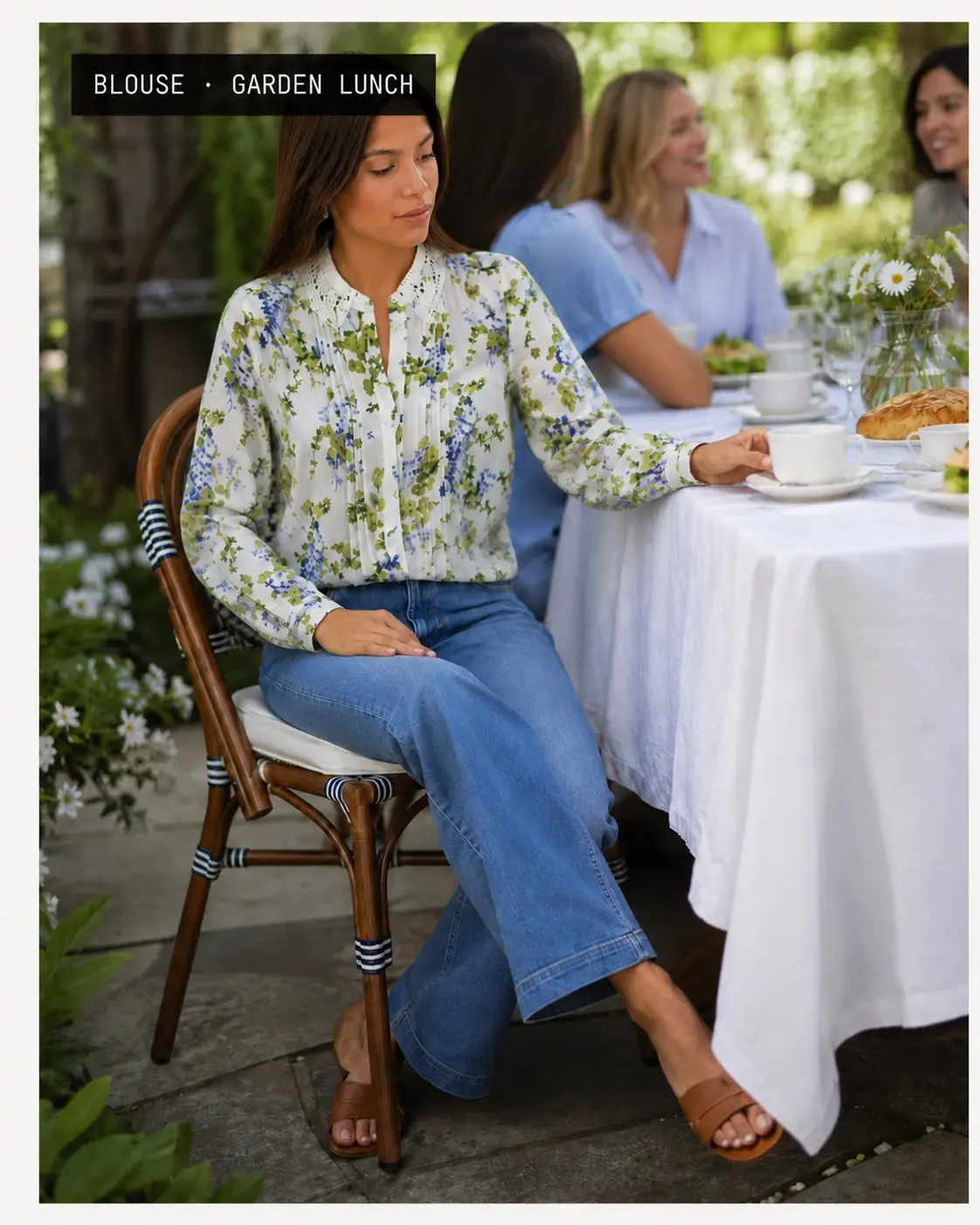 Model in a floral pintuck blouse at an outdoor garden lunch table