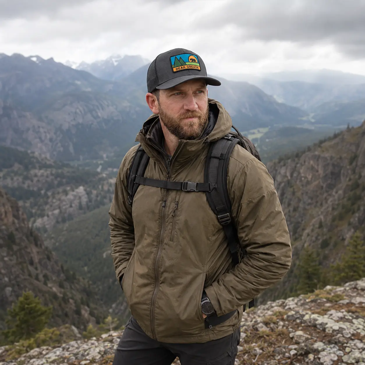 Portrait of a bearded man wearing the Bear Grease trucker hat on a mountain overlook