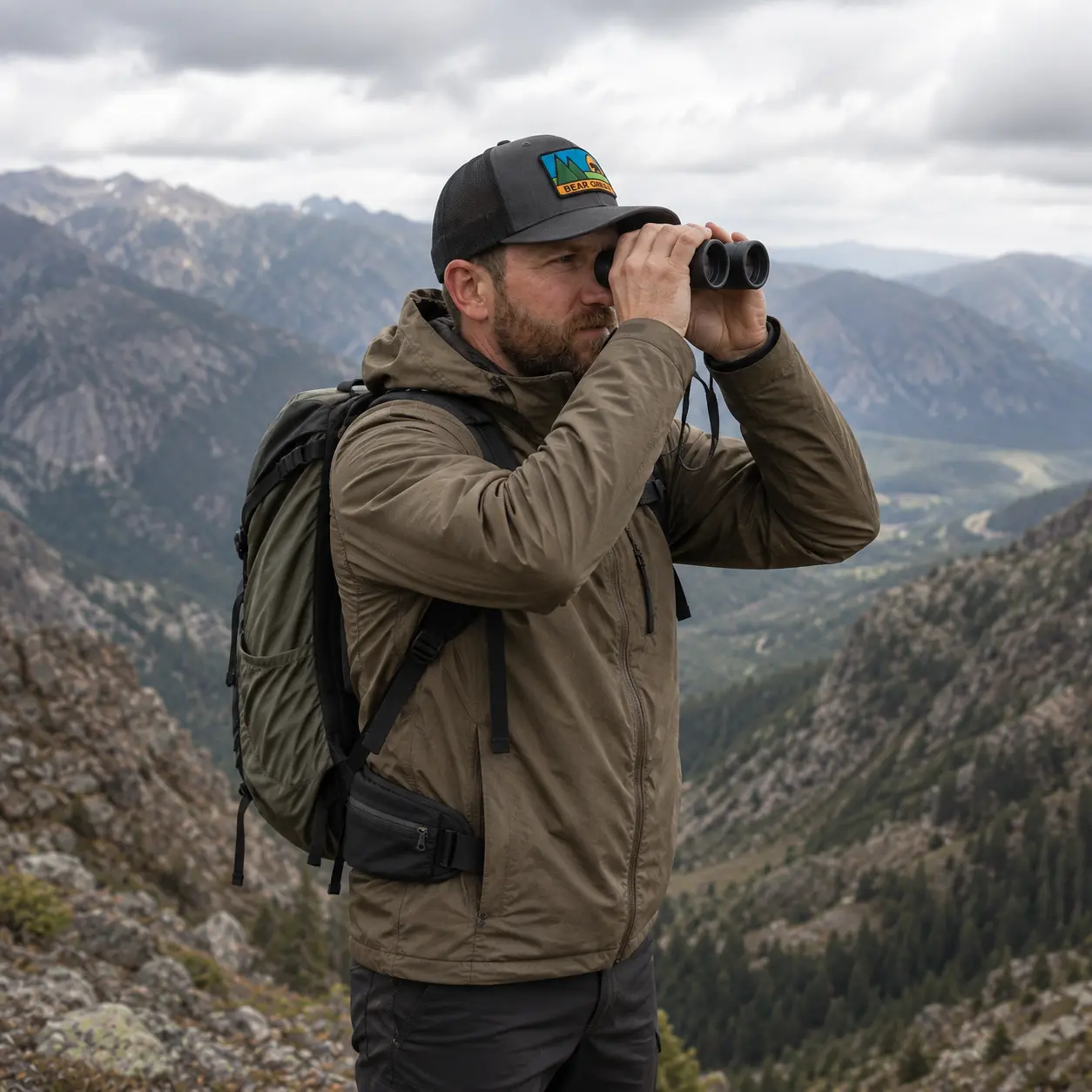 Model glassing with binoculars from a ridge wearing the Bear Grease trucker hat