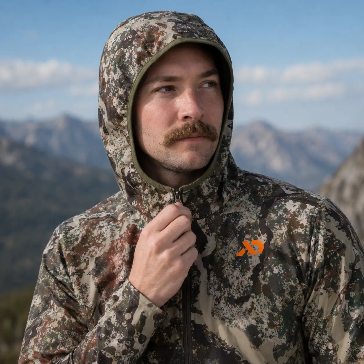 Tight portrait of the Navigator Hoody hood and quarter zip against a blue mountain sky